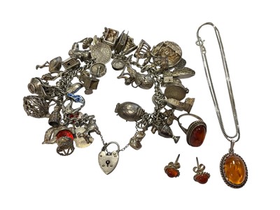 Lot 204 - Silver charm bracelet with an extensive collection of novelty silver charms, together with a silver and amber pendant, ring and earrings