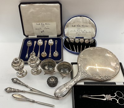 Lot 1101 - Box of assorted silver to include an embossed silver hand mirror, cased set of six coffee spoons, cased set of six teaspoons, pair of peppers, pair of salts etc