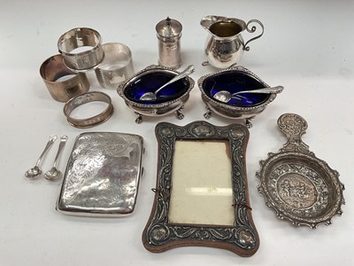 Lot 1071 - Group of silver to include pair of salts with blue glass liners, salt spoons, pepperette, cream jug, napkin rings, cigarette case, photograph frame and tea strainer