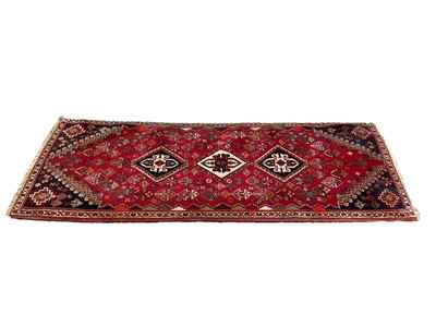Lot 1325 - Eastern runner with three central medallions on red and blue ground, 198cm x 74cm