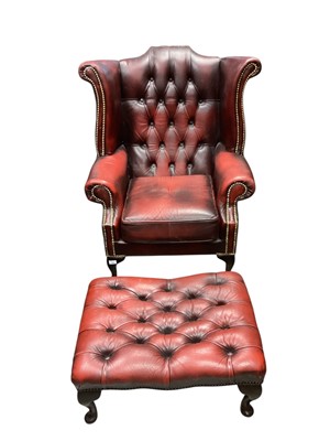 Lot 1391 - Georgian style oxblood leather wing back armchair and matching footstool (2)