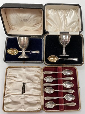 Lot 1157 - Two cased silver eggs cups and spoons, together with a set of six silver coffee spoons in fitted case