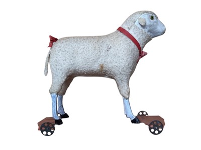 Lot 1820 - Two early Putz sheep with painted faces, green glass eyes, wool plush and wooden stick legs, 15cms and 18cms approximately . Plus similar dog with amber glass eyes 15cms.