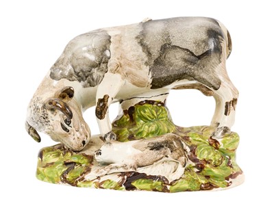 Lot 229 - A rare early 19th century pearlware glazed cow and calf group, painted in tones of black and grey, on a naturalistic base, 13.5cm high x 17.5cm wide