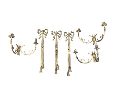 Lot 1425 - Set of three gilt metal two branch wall lights, in the rococo style with ribbon cresting and twin branches, 54cm high
