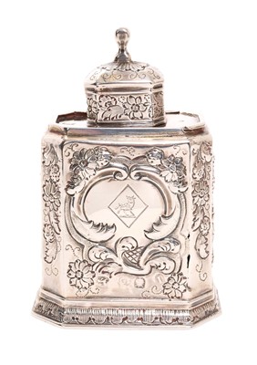 Lot 269 - George I silver tea caddy of elongated octagonal form with sliding top and detachable lid, all over later decorated with repousse floral and scroll motifs, the cartouche with engraved crest (Lon...