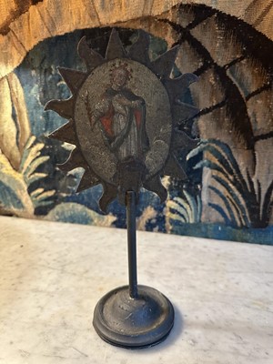 Lot 1513 - 19th century, or earlier, painted metal double-sided table screen depicting figures within a sunburst, on circular base