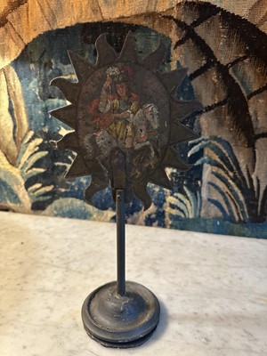 Lot 1513 - 19th century, or earlier, painted metal double-sided table screen depicting figures within a sunburst, on circular base