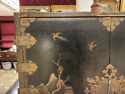 Lot 1522 - Late 17th / early 18th century Chinese lacquer cabinet on stand, the twin hinged doors decorated with landscapes, brass strap hinges, enclosing an arrangment of drawers, on square legs
