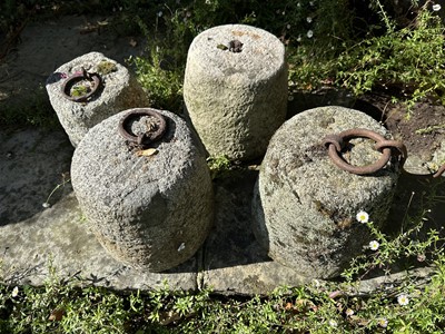 Lot 1934 - Four antique granite weights, three with cast iron rings, 24cm high