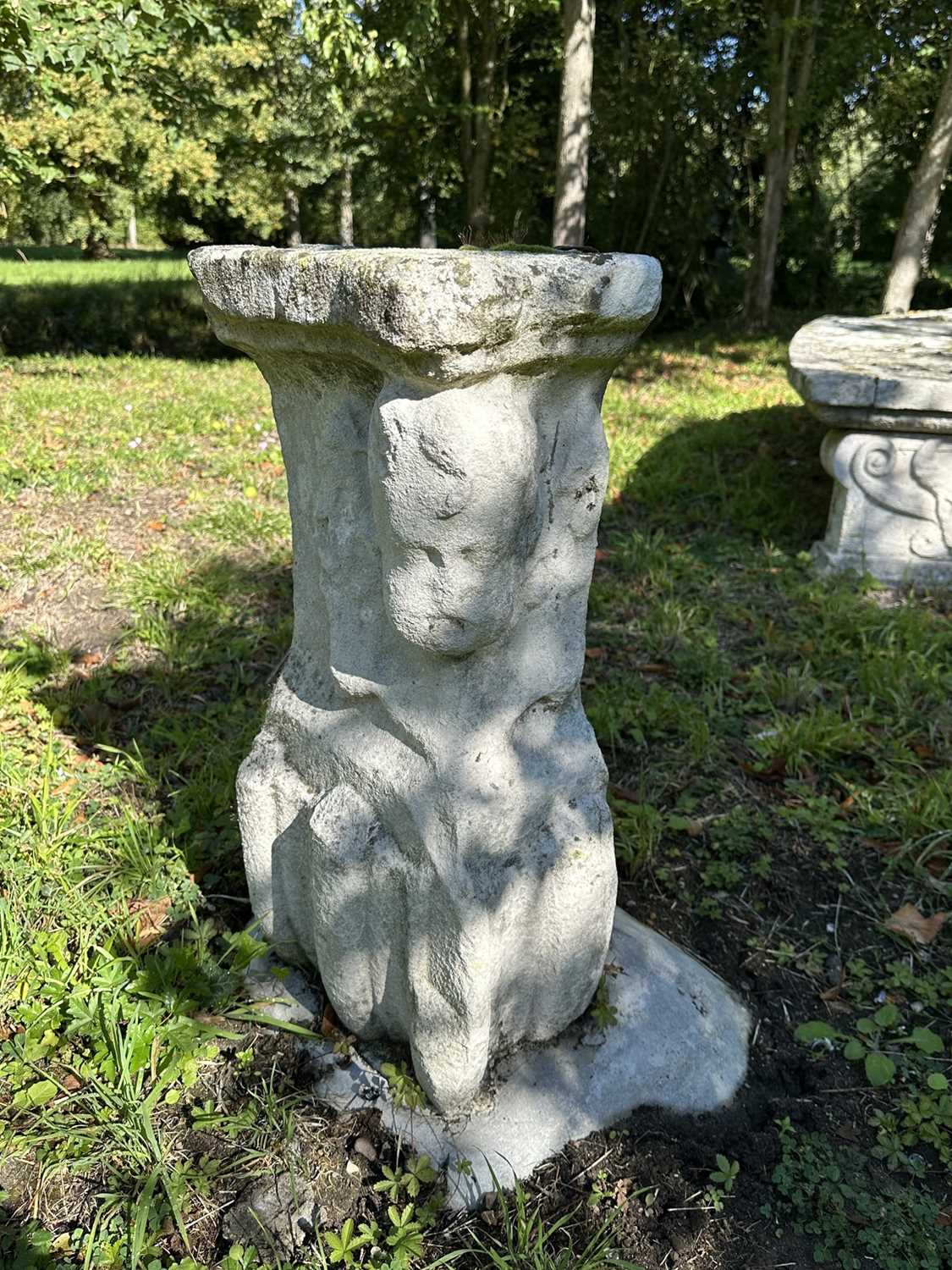 Lot 1935 - Pair of 17th / 18th century carved stone mounts, each with winged cherubic figures, approximately 70cm high, set into a concrete base