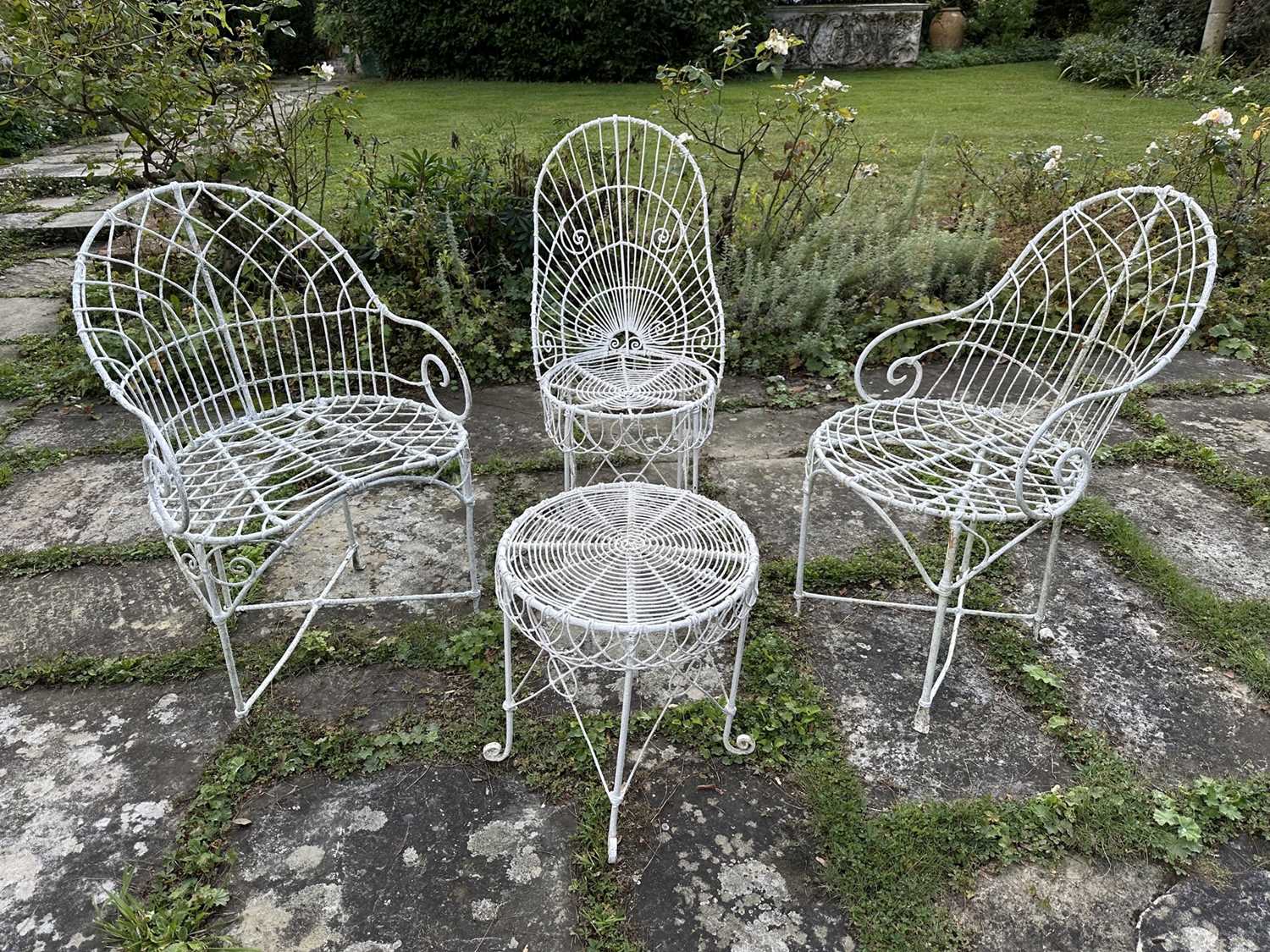 Lot 1957 - Group of white painted wire-work garden furniture comprising two elbow chairs, a standard chair and a low round table (4)