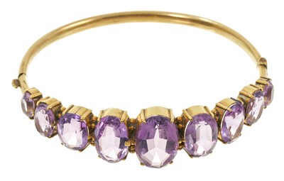 Lot 585 - Victorian amethyst hinged bangle with nine graduated oval mixed cut amethysts in gold setting