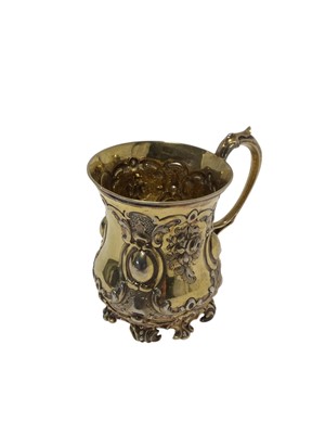 Lot 493 - Victorian silver gilt christening mug of baluster form with embossed decoration and scroll handle, raised on four scroll feet, (London 1851), maker G.R., 11.4cm in height, all at 6.5ozs.