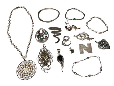 Lot 12 - Group of silver and white metal jewellery including various brooches, multi-gem set abstract silver pendant, synthetic opal silver disc pendant necklace, sterling bangle with hammered finish etc...