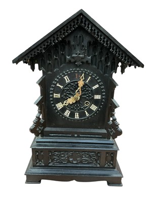 Lot 670 - Late 19th century Black Forest cuckoo mantel clock with carved ebonised architectural case , carved bone hands and Roman numerals, the movement striking on a gong . 63cm high. Pendulum and key p...
