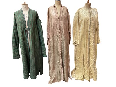 Lot 2509 - Two 1960s kaftans with braid trims and button fastening, pink lurex and gold paisley lurex.