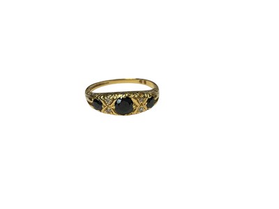Lot 114 - 18ct gold sapphire and diamond ring with three round mixed cut sapphires interspaced with four single cut diamonds in carved scroll setting, size N