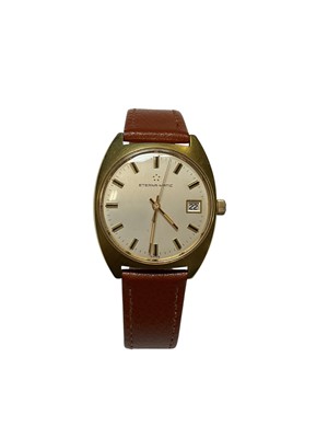 Lot 214 - 1960s Eterna-matic wristwatch with date aperture and centre seconds, in gold-plated tonneau shape case with brushed finish, on brown leather strap