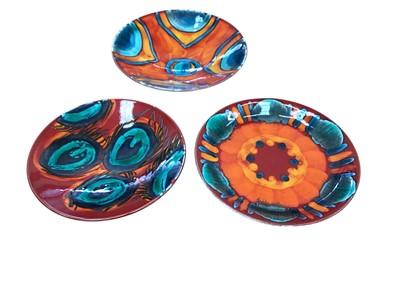 Lot 2267 - Two Poole pottery Peacock design bowls, 27cm and 25cm diameter, together with a Volcano charger, 27cm diameter (3)