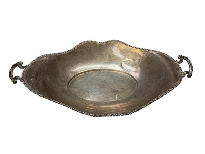 Lot 273 - George V silver cake dish of oval form with twin handles, raised on four hoof feet, (Birmingham 1919), 33.5cm in length.
