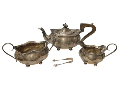 Lot 272 - George V silver three piece teaset comprising teapot of cauldron form with engraved decoration raised on four bun feet, together with matching milk jug and sugar bowl, (Birmingham 1910)