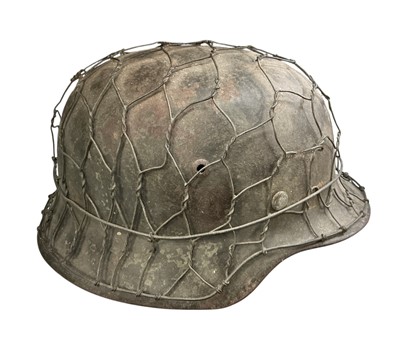 Lot 760 - Second World War Nazi German M40 pattern steel helmet, with original painted finish and chicken wire cover, stamped under brim 'SE66', '357' with tan leather liner.