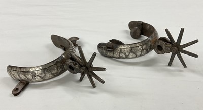 Lot 820 - Pair of Mexican cowboy spurs with applied silver decoration.