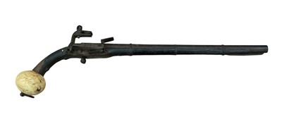 Lot 994 - 19th century Eastern Flintlock pistol with Miquelet- type lock, 28 bore barrel, button trigger with leather covered stock and ivory ball skull cracker pommel, 48cm overall