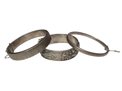 Lot 282 - 1970s silver bark effect hinged bangle, one other silver bangle and a Continental white metal bangle with fruit and floral decoration (3)