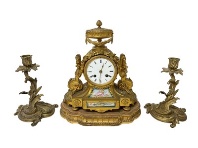 Lot 662 - Late 19th century French ormolu mantel clock with painted porcelain panels decorated with putto and flora, with urn surmount, 28.5cm high on gilt wood base and pair gilt brass rococo-style candl...