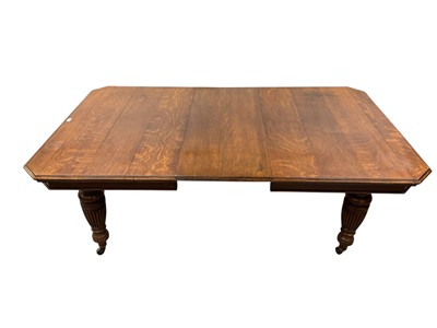 Lot 1482 - Edwardian blond oak extending dining table, with canted rectangular wind out top on bulbous fluted supports and castors, with two additional leaves, 124 x 150cm extending to 246cm