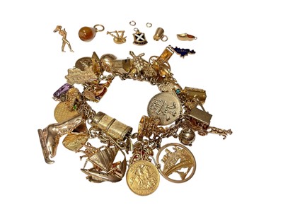 Lot 96 - 9ct gold charm bracelet with a good collection of gold and yellow metal charms including a George V half sovereign, 1913.