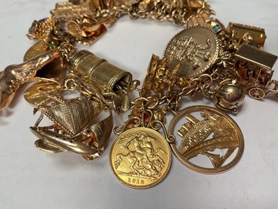 Lot 96 - 9ct gold charm bracelet with a good collection of gold and yellow metal charms including a George V half sovereign, 1913.