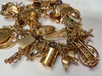 Lot 96 - 9ct gold charm bracelet with a good collection of gold and yellow metal charms including a George V half sovereign, 1913.