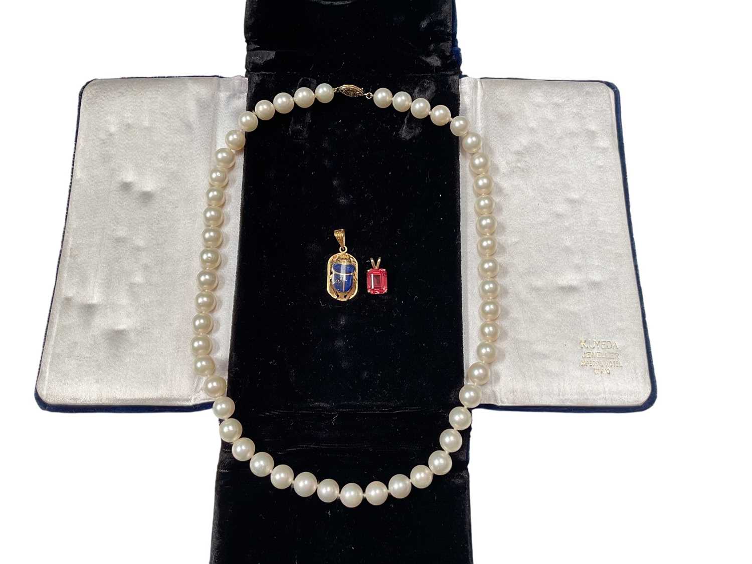 Lot 48 - Egyptian yellow metal and enamel scarab beetle pendant, 14k gold mounted pink stone pendant and a cultured pearl single string necklace with 14k clasp (3)