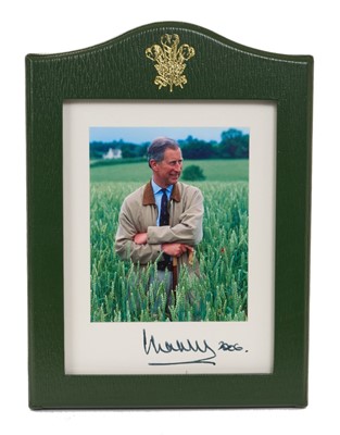 Lot 59 - H.R.H. Prince Charles, Prince of Wales (now H.M. King Charles III) signed 2006 Royal presentation portrait photograph of the Prince leaning on a stick in a field, in original green Morocco leat...