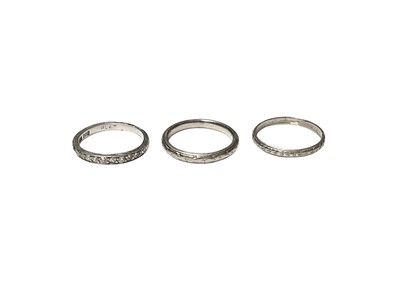 Lot 117 - Platinum and diamond half eternity ring and two platinum wedding rings with engraved decoration (3)