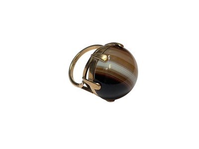 Lot 141 - 9ct gold banded agate cocktail ring with a round polished agate cabochon, measuring 20mm diameter, in gold six claw setting. Ring size N