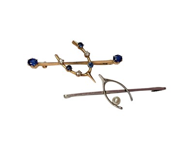 Lot 142 - Edwardian yellow metal sapphire and diamond wishbone bar brooch and another 9ct white gold and cultured pearl wishbone bar brooch (2)
