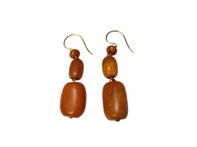 Lot 163 - Pair of amber pendant earrings with 18ct gold hook fittings, 50mm drop