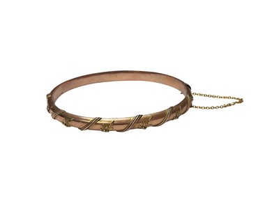 Lot 237 - Victorian 9ct rose gold hinged bangle with applied ribbon and foliate decoration (Chester 1894)