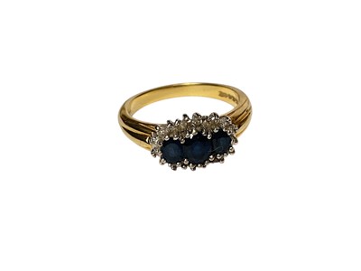Lot 231 - 18ct gold sapphire and diamond ring with three oval mixed cut blue sapphires surrounded by a border of diamonds