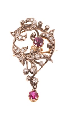 Lot 553 - Edwardian Art Nouveau ruby and diamond pendant brooch with an asymmetric floral scroll set with a central mixed cut ruby within old cut diamond scrolls, suspending a further ruby drop, in silver...