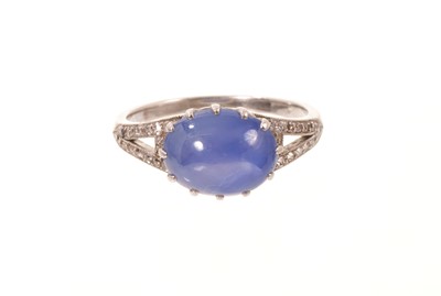 Lot 560 - Edwardian star sapphire and diamond ring with an oval blue star sapphire cabochon measuring approximately 9.8mm x 7.9mm x 5.1mm, with old cut diamonds to the open shoulders in millegrain setting...