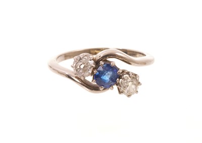 Lot 582 - Edwardian sapphire and diamond three stone cross-over ring with a central mixed cut blue sapphire flanked by two old cut diamonds in claw setting