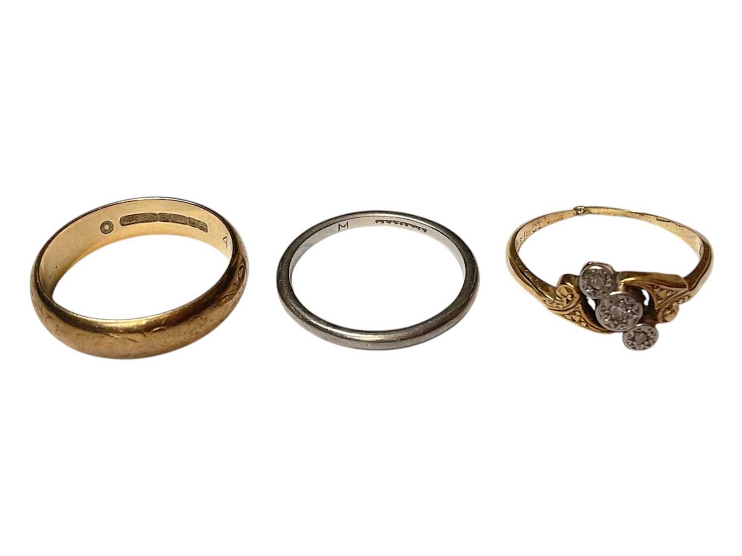 Lot 32 - 9ct gold wedding ring, platinum wedding ring and 18ct gold diamond three stone cross-over ring (3)