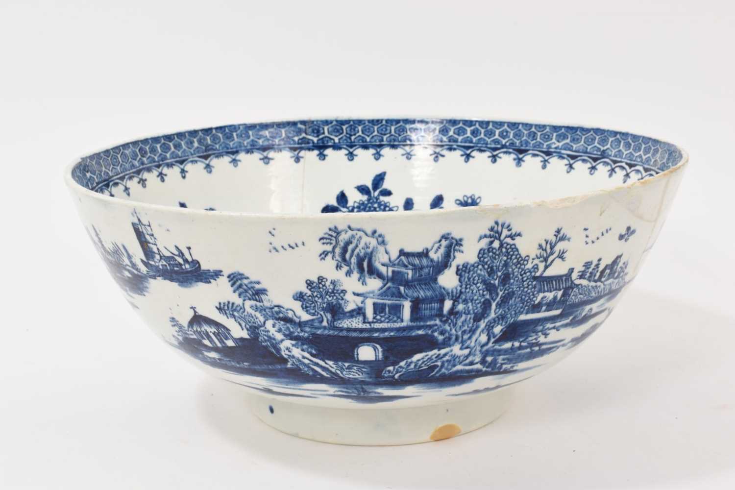 Lot 5038 - Lowestoft blue and white punch bowl, circa 1775, printed to the exterior with figures in a Chinese island landscape, with further similar landscape vignettes, the interior with floral sprays and...