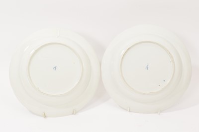Lot 5037 - Two 18th century Furstenberg porcelain shallow plates, painted with floral sprays and swags, the edge moulded with scrollwork cartouches, underglaze blue 'F' mark to bases, 23.75c diameter