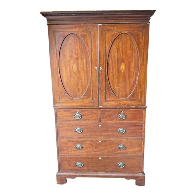 Lot 1486 - George III mahogany linen press, the upper section with slides, enclosed by a pair of shell patera inlaid oval panel doors, the base with three short over three long graduated drawers on bracket...